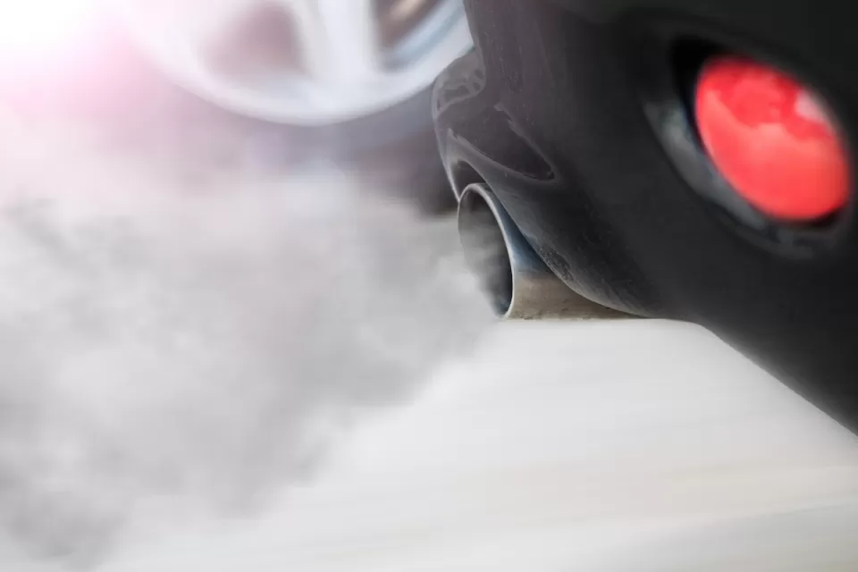 Close-up of car tailpipe with smoke coming out.